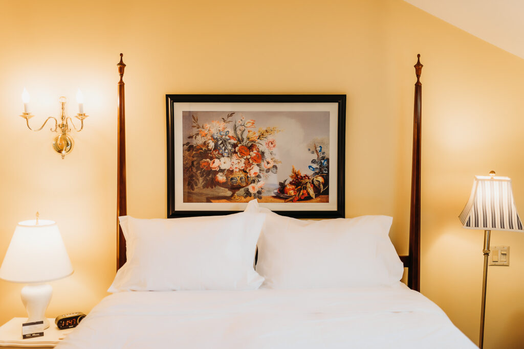 A photo of flowers above a comfortable bed.