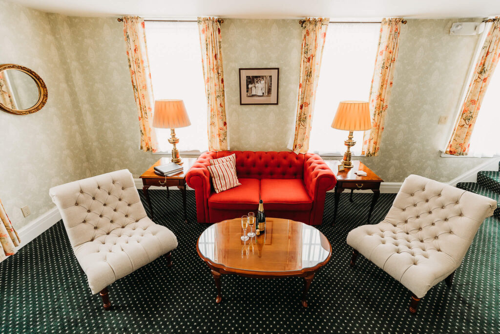 Sitting room with two comfortable chairs, a large couch, and champagne sitting on the coffee table.