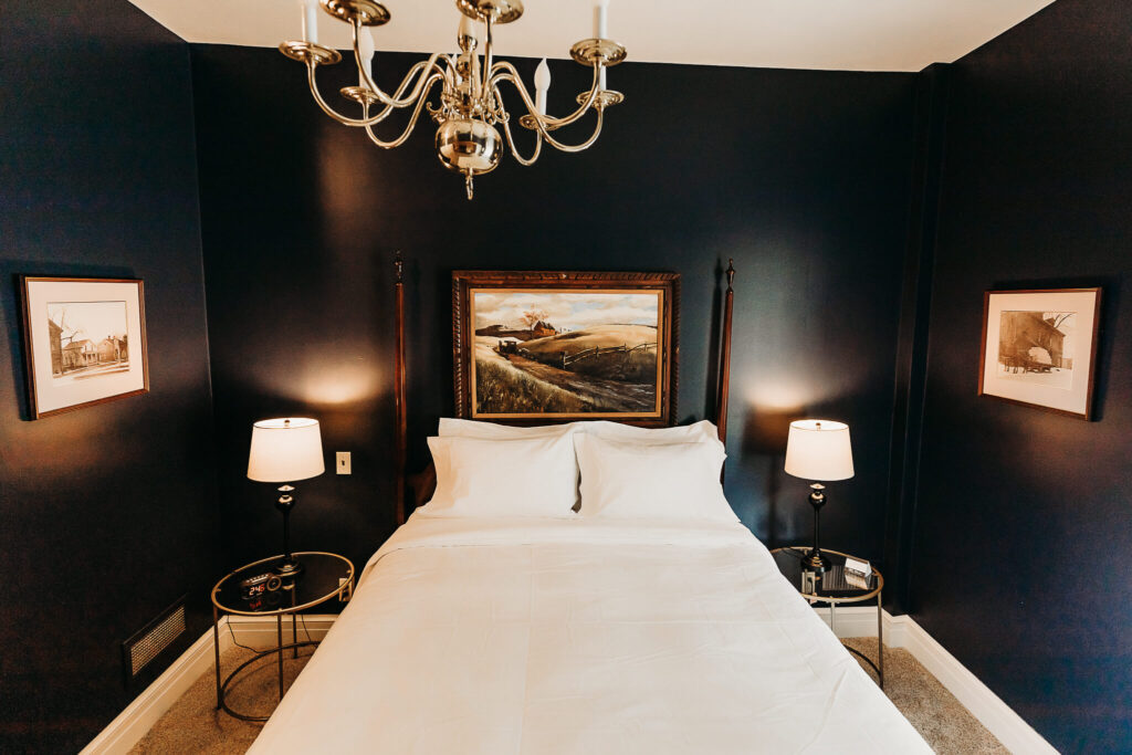 Large and comfortable bed in the guest room that is underneath a polished chandelier.