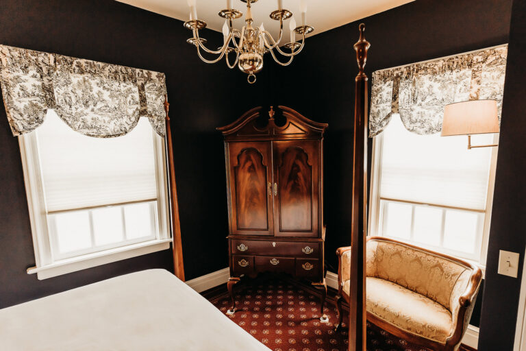 Large Wardrobe with a chandelier above framed by two large windows bringing in natural lights to the guest room.